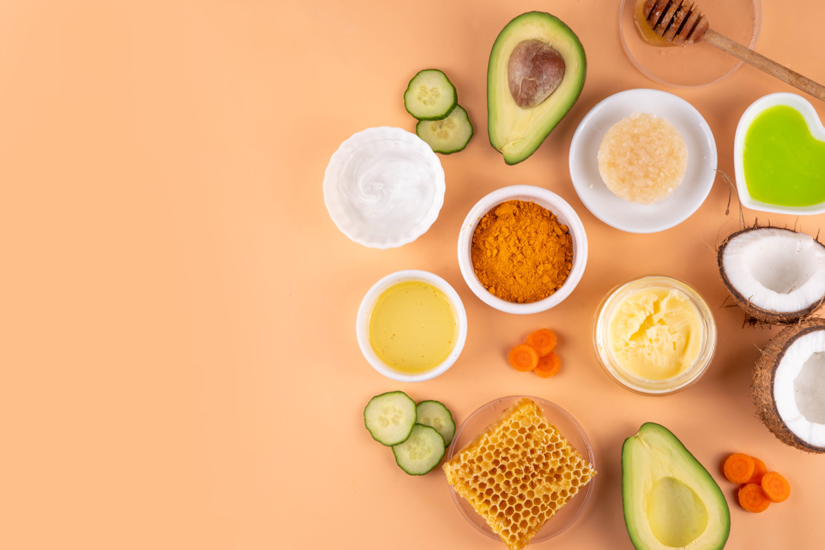 Zutaten für DIY Sonnenlotion mit Avocado, Kokosöl, Kurkuma, Honig und Gurke auf hellem Hintergrund.