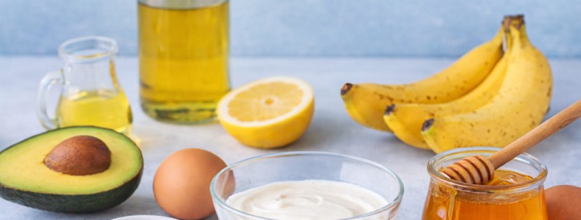 Zutaten für natürliche Haarkur mit Avocado, Banane, Honig, Joghurt, Ei, Öl und Zitrone.